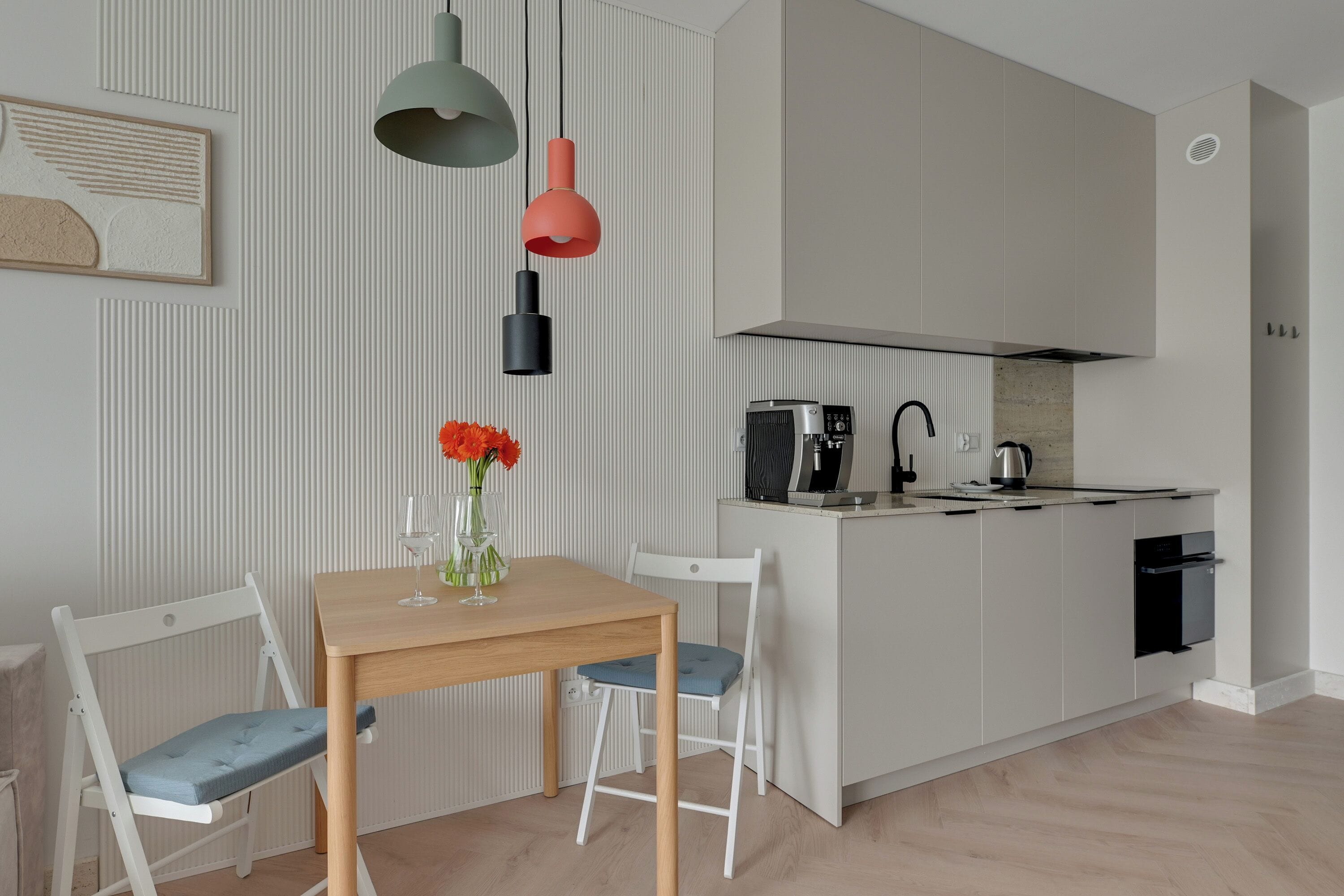 A modern kitchen with white cabinetry, a wooden dining table, and two chairs.