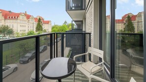 Ein Balkon mit Tisch und Stühlen, Blick auf Gebäude und bewölkter Himmel.