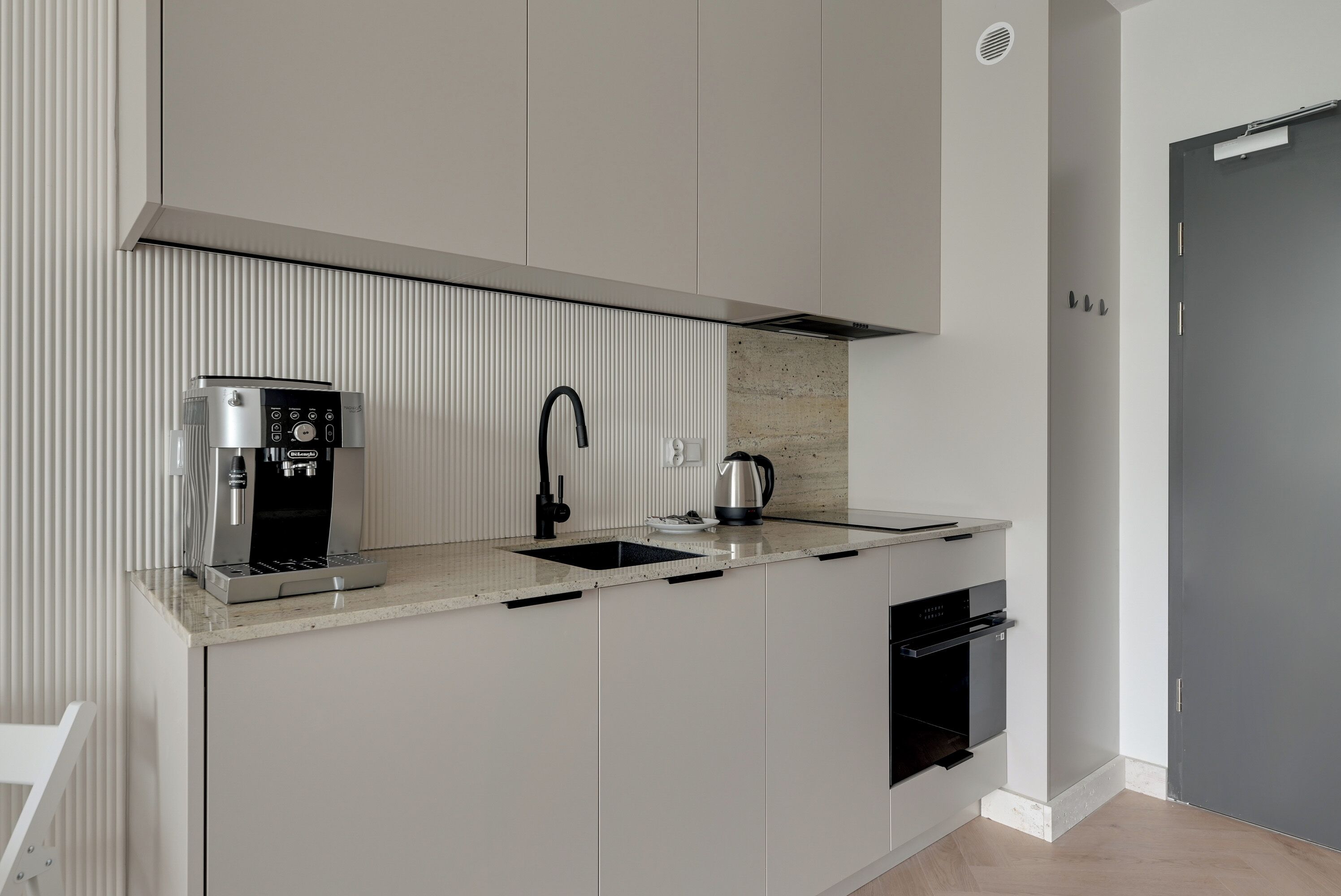 Una cocina moderna con cafetera, hervidor y horno empotrado.