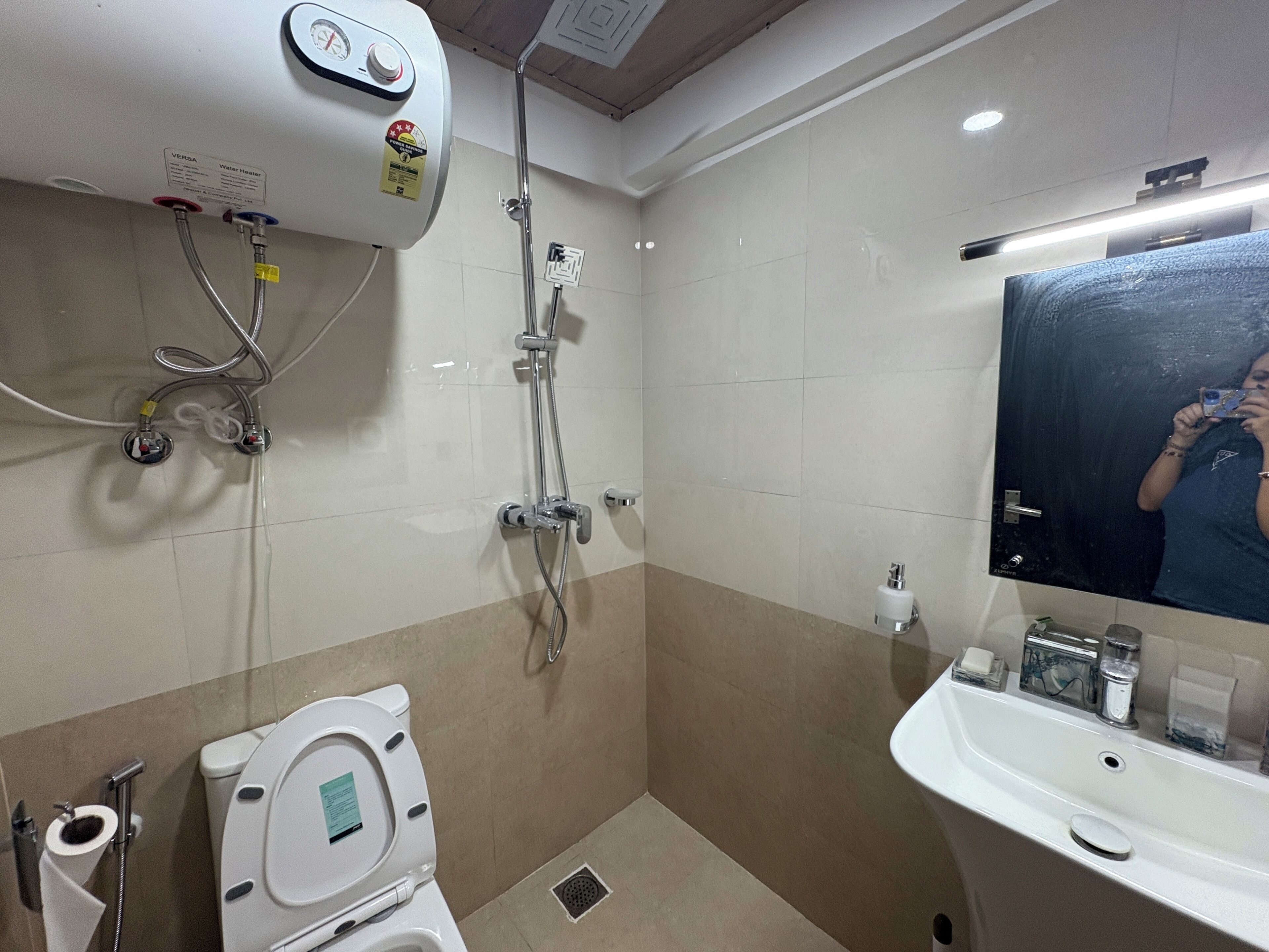 Un baño con inodoro, lavabo, espejo y ducha.
