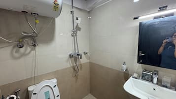 Un baño con inodoro, lavabo, espejo y ducha.