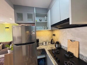 Moderni keittiö, jossa on ruostumattomasta teräksestä valmistettu jääkaappi, kaasuliesi ja sisäänrakennettu uuni.