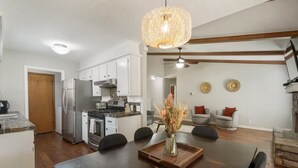 Een moderne keuken met een eethoek, een houten plafond en een decoratieve vaas op tafel.