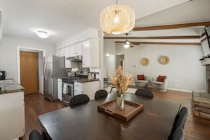 Une cuisine moderne avec un coin repas, un plafond en bois et un vase décoratif posé sur la table.