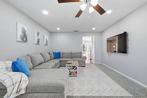 A modern living room with a sectional sofa, a coffee table, and a flat-screen TV mounted on the wall. - “The Pearl” Family House, 6-10 Minutes to Downtown, Alamodome, Frost Center (San Antonio)