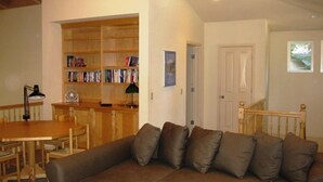A cozy living room with a sectional sofa, a wooden bookshelf, and a dining table. - Droge-Yuklois, LACC in Lake Almanor, CA (Lake Almanor)