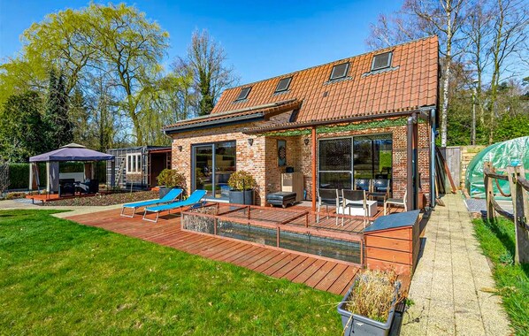 A modern house with a patio, outdoor seating, and a covered area.