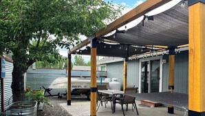 A covered patio area with a table and chairs, a grill, and a water heater. - Lakeside Retreat in Chester, CA (Chester)