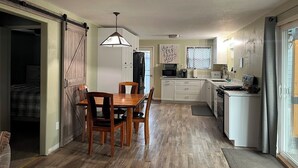 A compact kitchen with a dining area, a sliding door leading to a bedroom, and a small window with curtains. - Lakeside Retreat in Chester, CA (Chester)