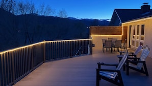 A deck with chairs and a table, a wooden fence, and a building with windows. - 20 minutes to Monarch w/ Hot Tub & Game Room! (Salida)