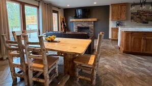 A dining area with a wooden table and chairs, a fireplace, and a kitchen with wooden cabinets. - 20 minutes to Monarch w/ Hot Tub & Game Room! (Salida)
