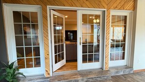 A wooden interior with three glass doors leading to a kitchen area. - 20 minutes to Monarch w/ Hot Tub & Game Room! (Salida)