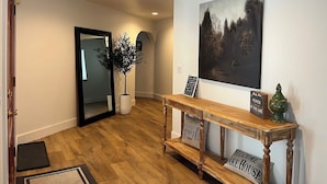 A hallway with wooden flooring, a mirror, a potted plant, a welcome sign, and a framed artwork on the wall. - Rice in Lake Almanor West, CA (Lake Almanor West)