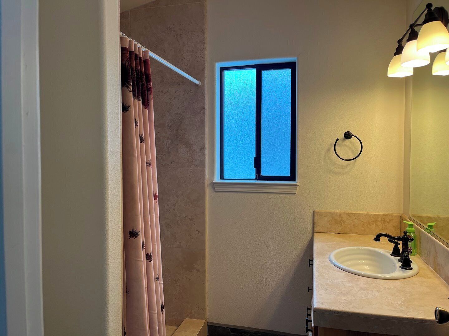 A bathroom with a window, a sink, and a shower curtain.