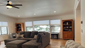 A spacious living room with a sectional sofa, ottoman, and a small table. There is a bookshelf and a ceiling fan. - Rice in Lake Almanor West, CA (Lake Almanor West)