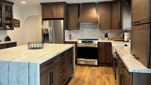 A modern kitchen with wooden cabinets, stainless steel appliances, and a marble countertop. - Rice in Lake Almanor West, CA (Lake Almanor West)