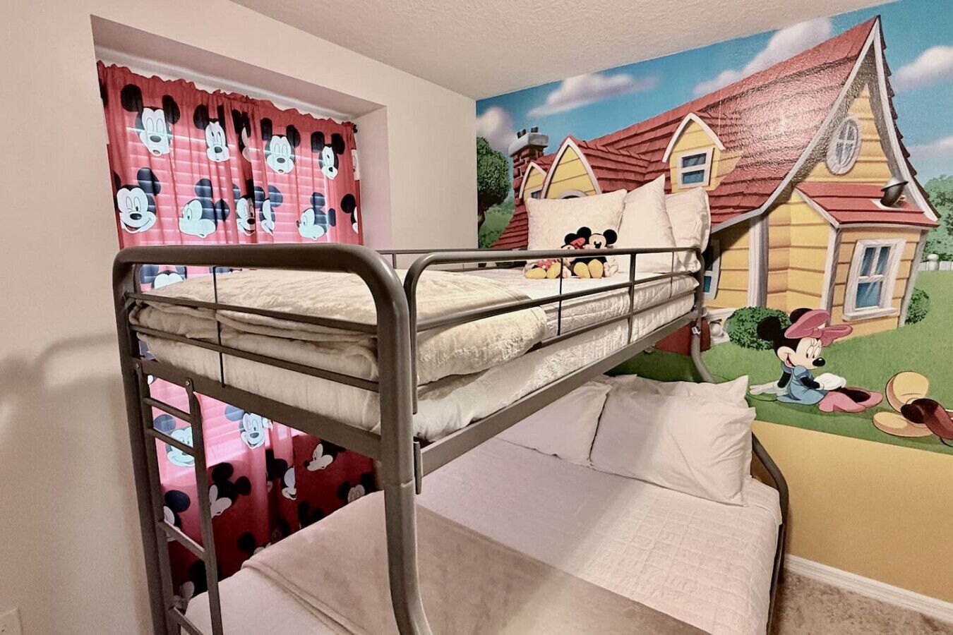 A bunk bed with a Mickey Mouse themed curtain and a mural of a cartoon house.