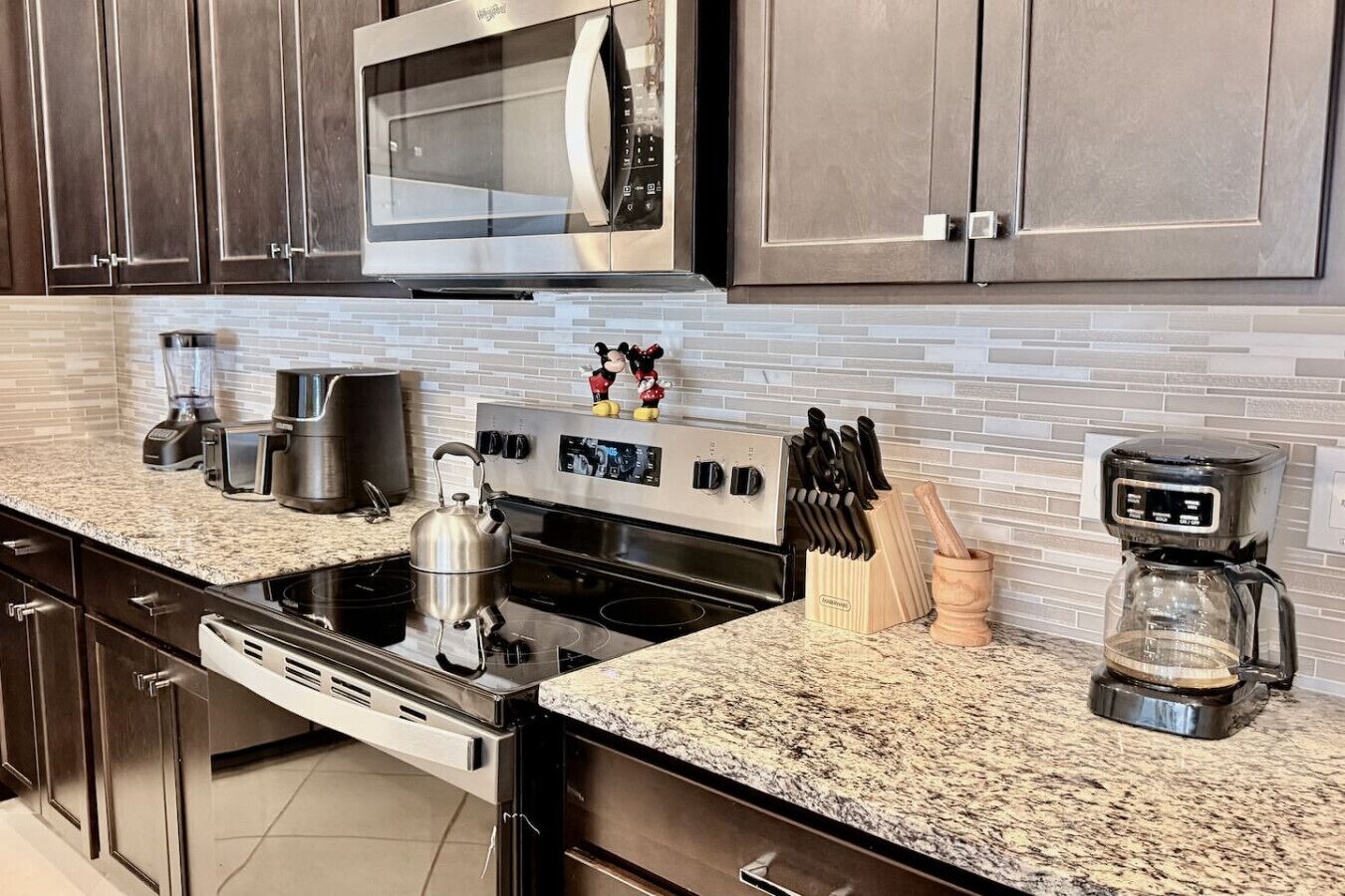 A modern kitchen with stainless steel appliances, a granite countertop, and a coffee maker.