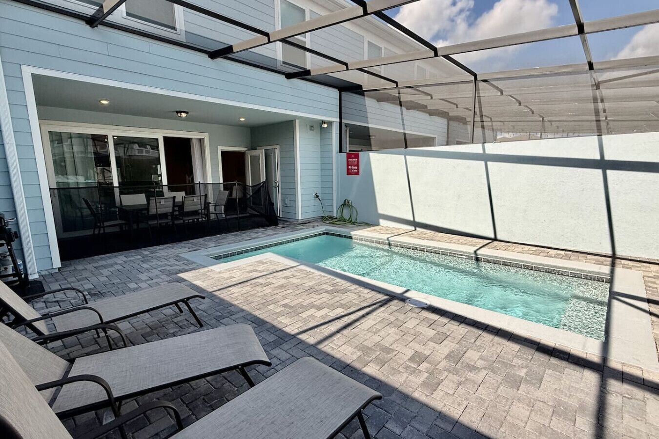 Uma área de piscina com um alpendre coberto, espaço para sentar ao ar livre e vista para o edifício.