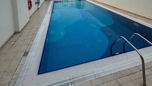 Ein Pool auf dem Dach mit freiem Blick auf die Stadtlandschaft, darunter ein markanter Wolkenkratzer.