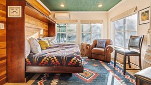 Una habitación con cama, una silla, un escritorio y una ventana.