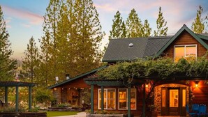 Une cabane en rondins avec des fondations en pierre, un revêtement extérieur en bois et une véranda dotée de sièges d’extérieur.