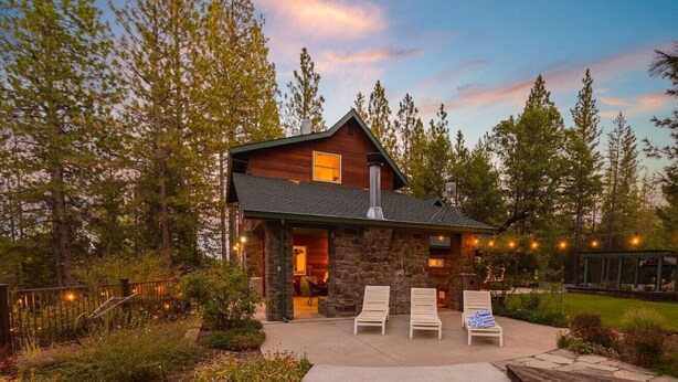 Une cabane rustique avec une façade en pierre, une cheminée et une terrasse équipée de chaises longues.