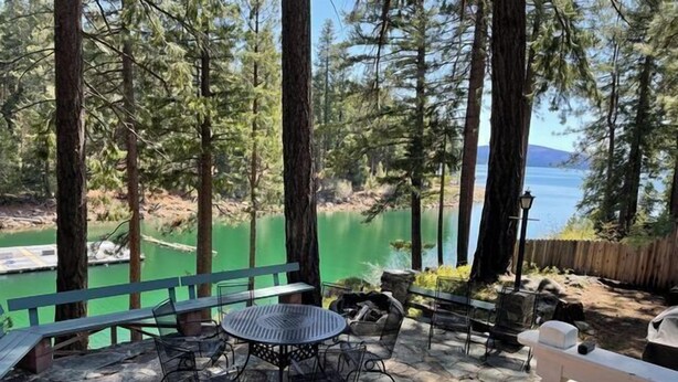 A patio with stone flooring, a round table, and metal chairs. - The Emerald Lake House (Lake Almanor)
