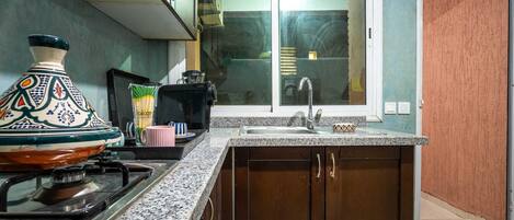 Una cocina con estufa a gas, un lavamanos y una ventana con vistas al exterior.