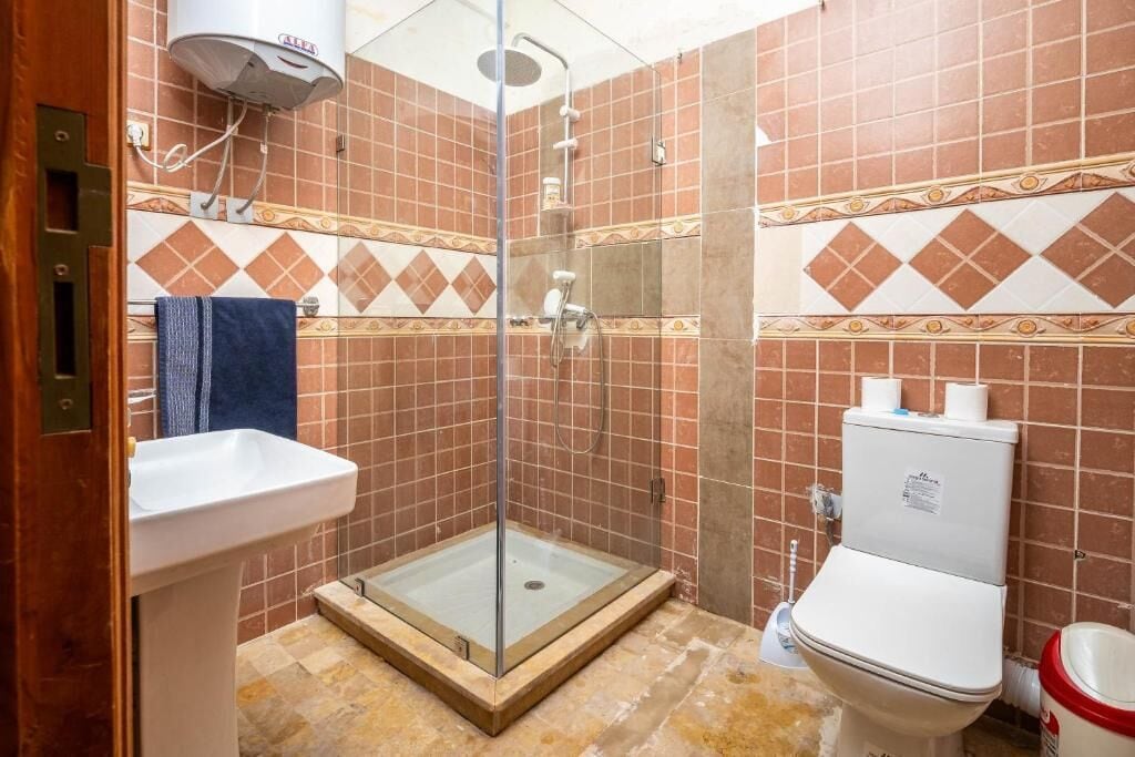 Un baño con ducha acristalada, lavabo pedestal y retrete.