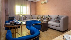 A living room with a sofa, two blue armchairs, a coffee table, and a decorative lamp.
