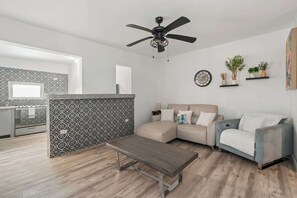 Ein modernes Wohnzimmer mit einer Couch, einem Couchtisch und einer Küchenzeile mit ornamental gestalteter Spritzschutzwand.