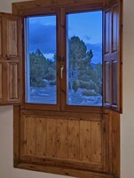 Un gabinete de madera con dos puertas de cristal, cada una mostrando una vista de un paisaje rocoso con árboles.