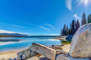 A clear lake with a rocky shoreline and trees in the background.