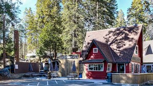 Un edificio rojo con un letrero que dice 'Burgers & Fries' y 'Hungry Hut' en un área boscosa con mesas de picnic.