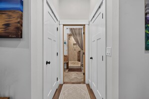 Hallway with white paneled doors, wood trim, and a view into a tiled walk-in shower behind a beige curtain. - Beautiful 4 bedroom home with loft in downtown Coeur d'Alene (Coeur d'Alene)