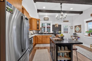 Eine moderne Küche mit Holzschränken, einem Edelstahlkühlschrank und einer zentralen Kochinsel mit Spüle.