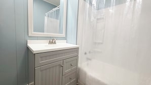 Un baño con un lavamanos blanco, un espejo y una bañera.