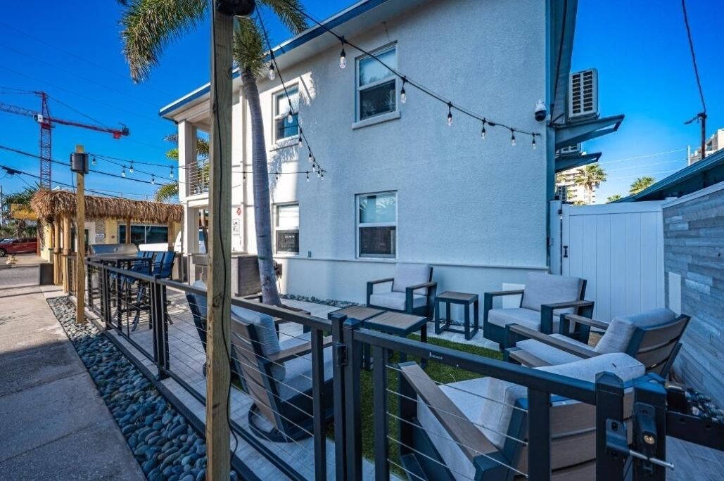 A modern building with a white exterior, outdoor seating area with tables and chairs, and a fenced patio.