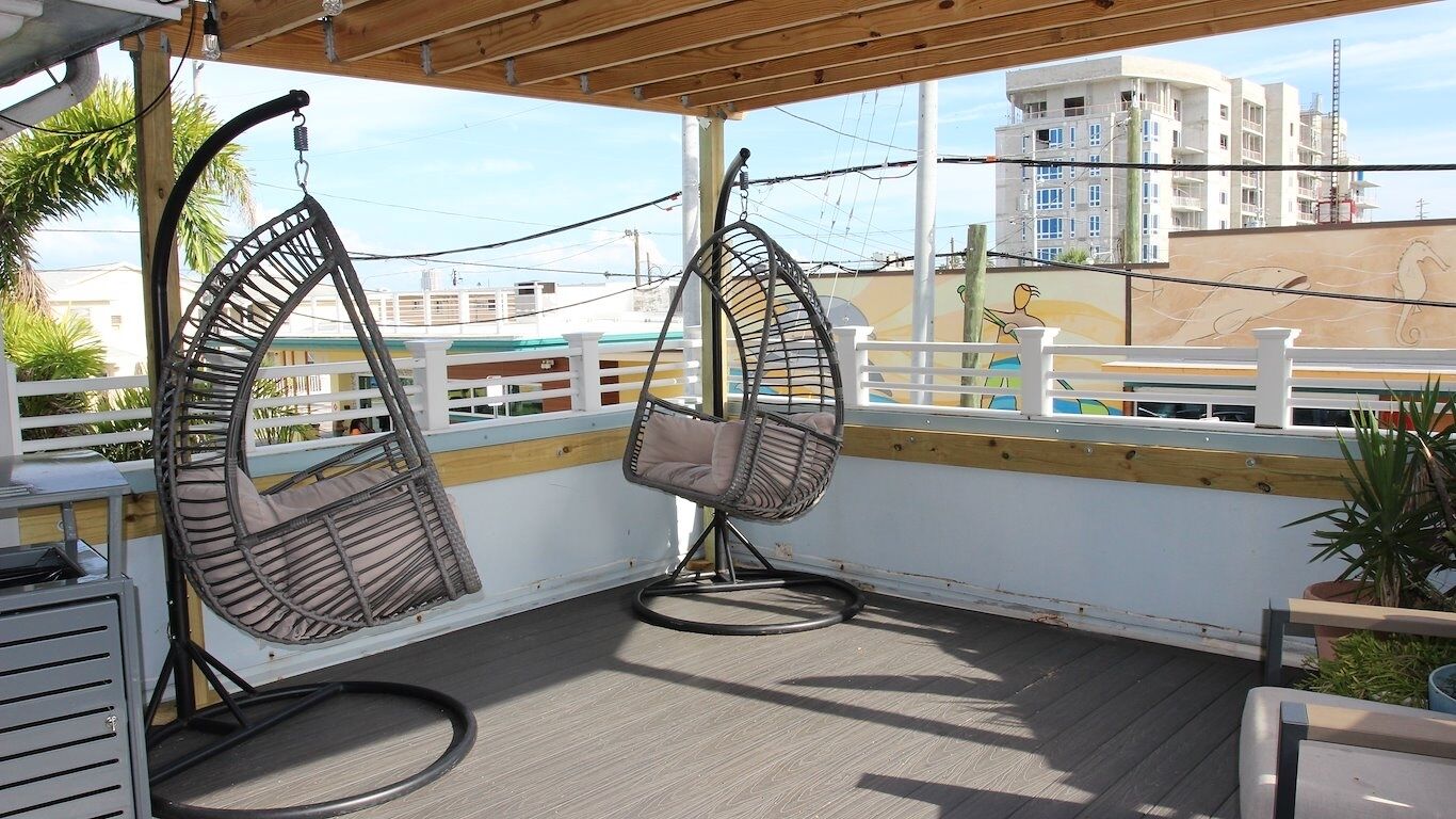 En balkon med to hængestole og udsigt til bygninger i baggrunden.