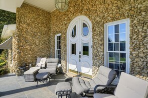 A stone exterior with a covered patio area featuring outdoor furniture and a door with glass panels. - Dalton Retreat w Deck and Fire Pit (Dalton)