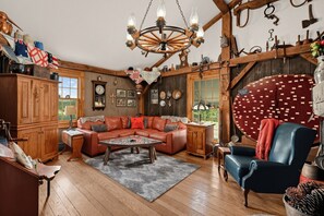 A cozy living room with a leather sofa, a wooden coffee table, and a chandelier. - Dalton Retreat w Deck and Fire Pit (Dalton)