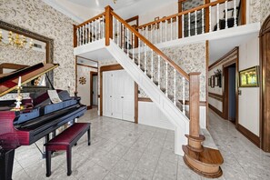 A grand piano in a spacious room with a wooden staircase and a chandelier. - Dalton Retreat w Deck and Fire Pit (Dalton)