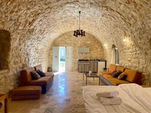 A cozy room with a stone ceiling, a sofa, a bed, and a small kitchen area. - Domaine de Filia (Aalali)