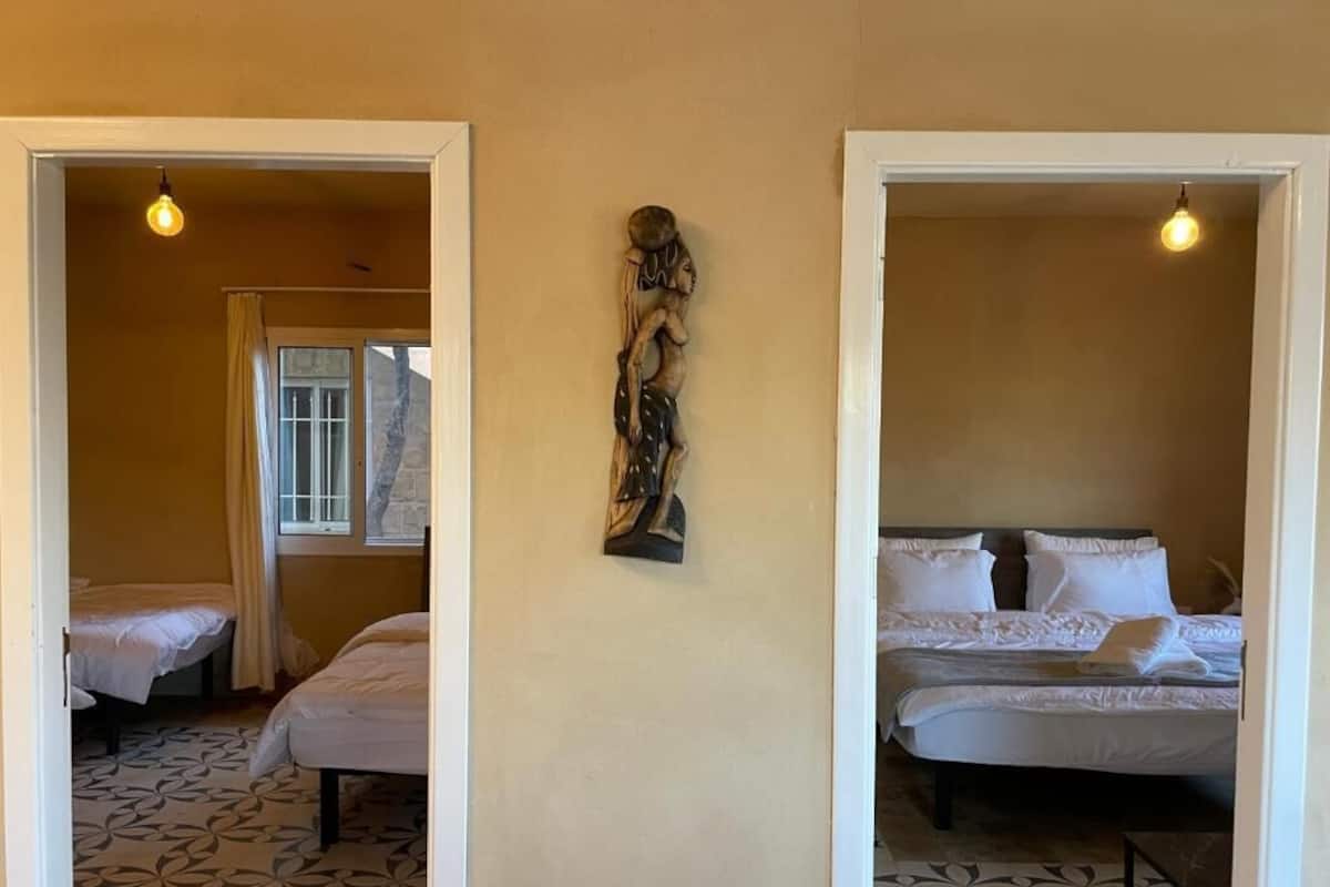 Habitación de hotel con dos camas, piso estampado y una escultura en la pared.