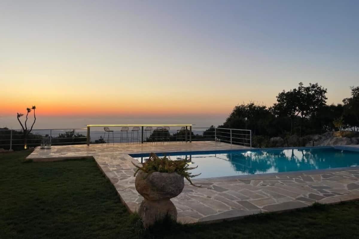 Una piscina con cubierta de piedra, rodeada de césped y árboles.