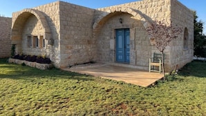 A stone building with a central arched entrance and a blue door. - Domaine de Filia (Aalali)