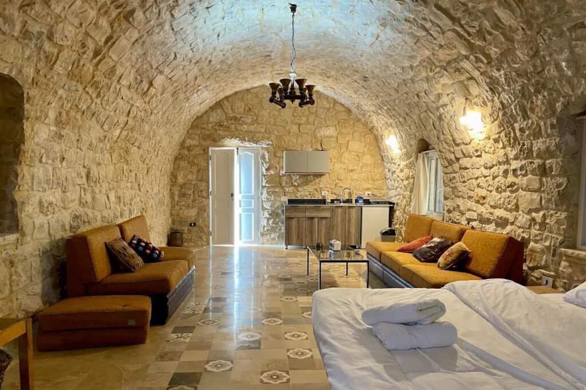 Una habitación acogedora con techo de piedra, una cama, un sofá y una pequeña cocina.