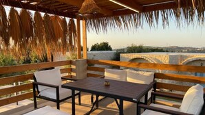 An outdoor seating area with wooden furniture and a stone wall backdrop. - Domaine de Filia (Aalali)