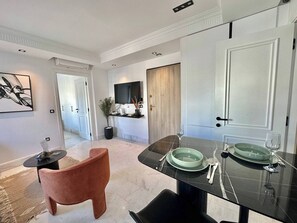 A modern dining area with a marble floor, a black dining table set with green plates, and a pink chair. - Irina Cozy Urban Refuge in the Heart of La Marsa (La Marsa)